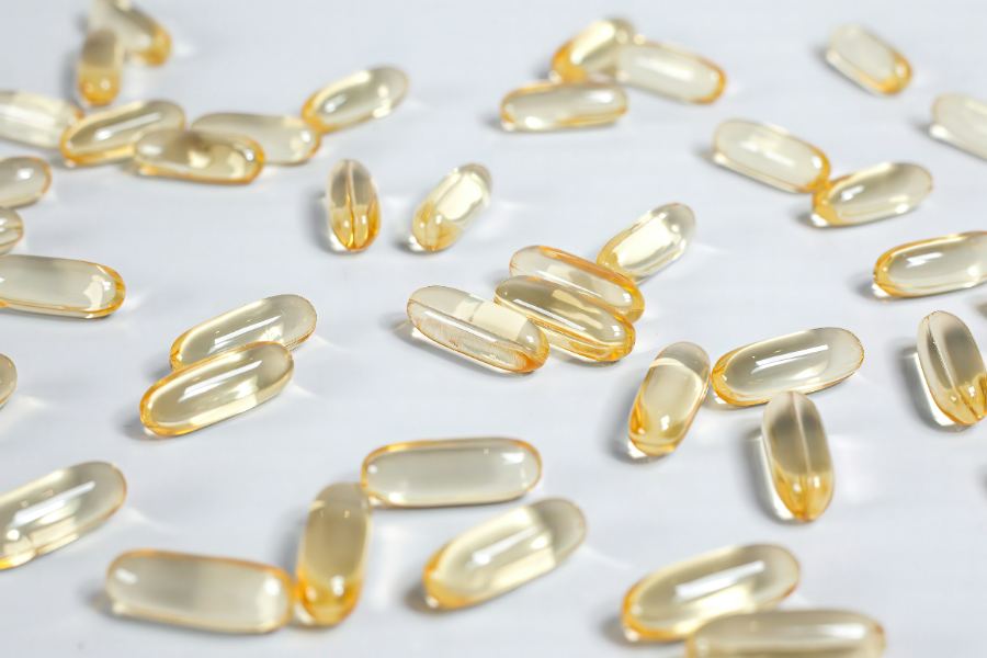 Pale gold softgels spread evenly across a white surface.